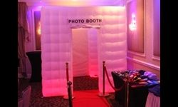 A Sweet 16 with our enclosed photobooth with Red Carpet upgrade. Inflatable photo booth with a red carpet and prop table set up in a dimly lit event room.
