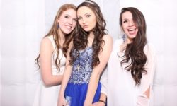 This photo came from inside our enclosed photobooth which is 8'x8' and lights up as well!! Three young women in formal dresses pose together against a white backdrop, smiling and making faces at the camera.