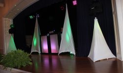 DJ set up on the stage with a packed room of guests.