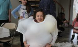 A kids birthday party at a house with a fun game of "Stuff that Shirt". Here we place balloons under an oversized t-shirt. How many can they fit.